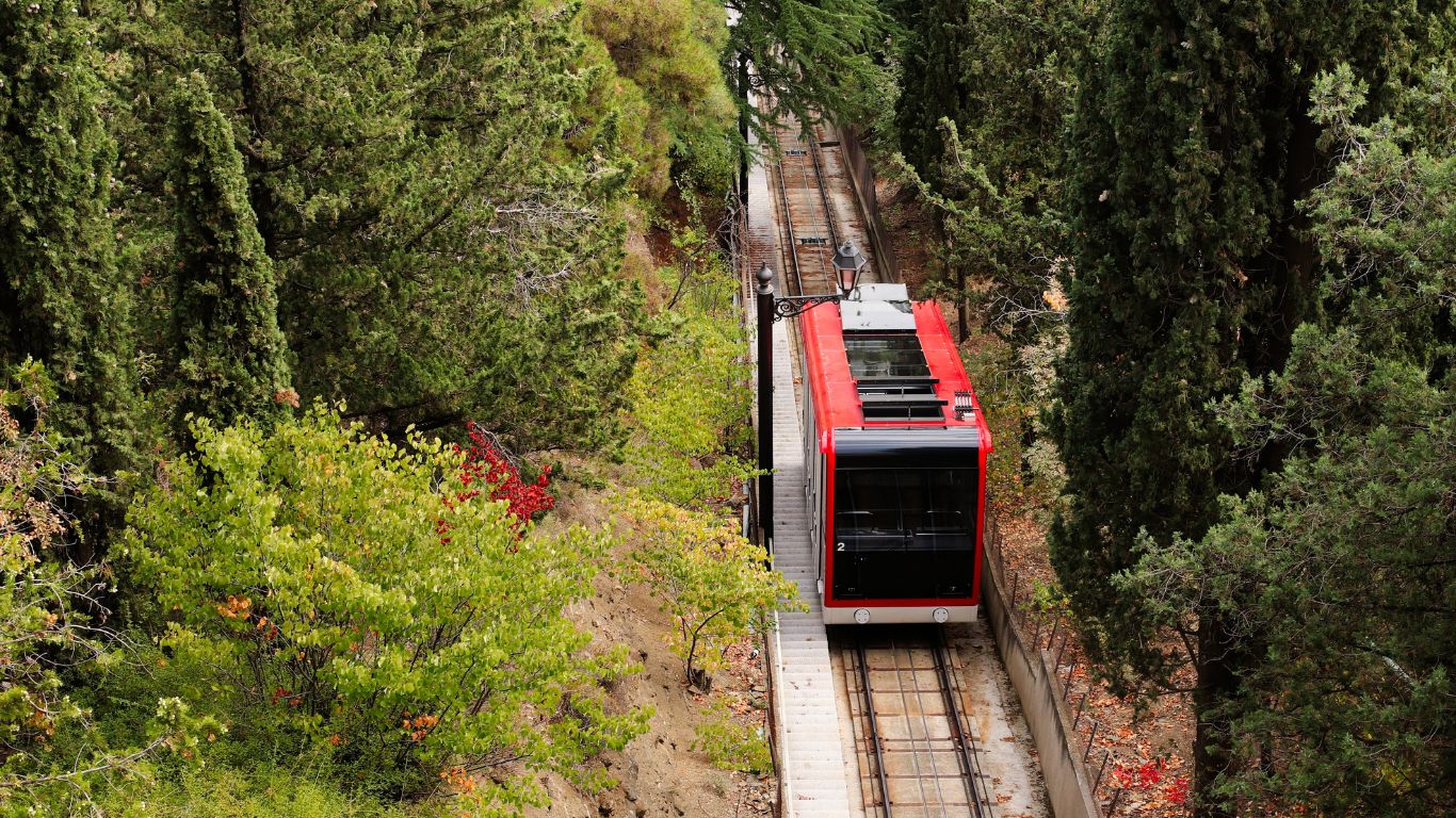 A scenic train winding through Andrews Valley, showcasing lush landscapes and majestic mountains.